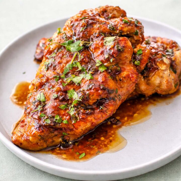 Honey garlic chicken breast with glossy sauce and fresh parsley served on a plate.