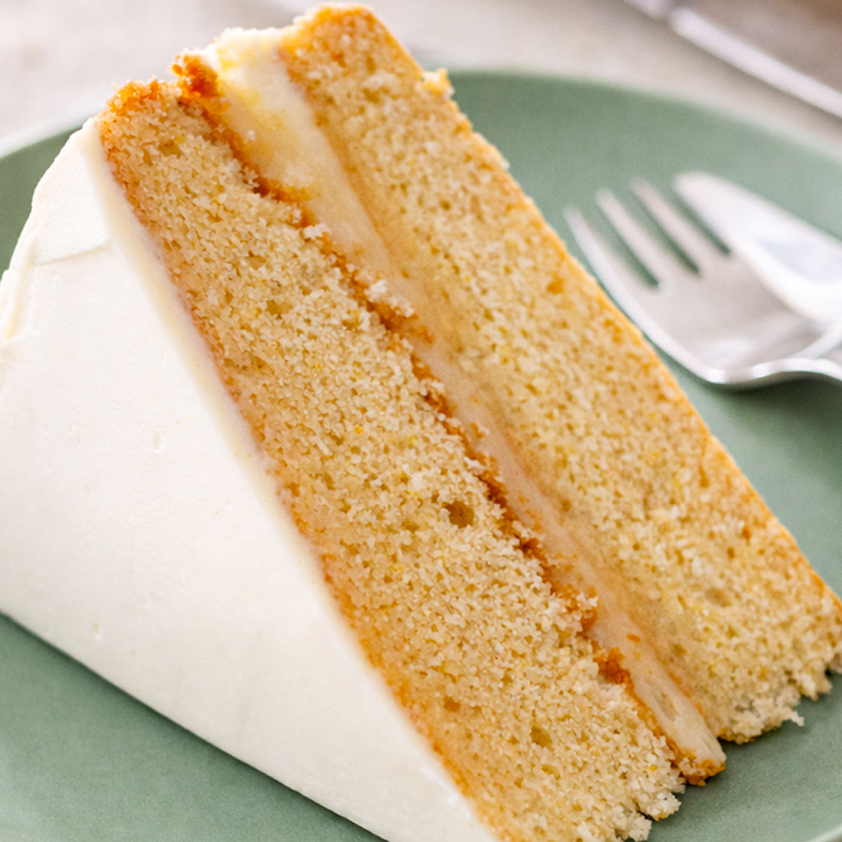 Close-up of a lemon curd layer cake slice with cream cheese frosting showing soft lemon sponge and tangy lemon curd filling.