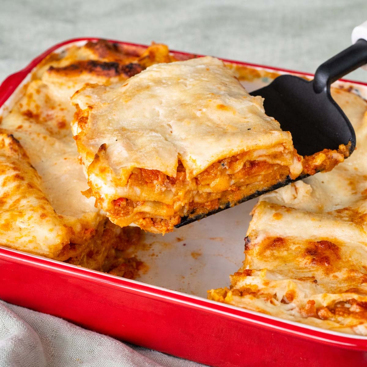 Easy no-boil lasagna slice with pork Bolognese, béchamel sauce, and melted cheese served from a baking dish 