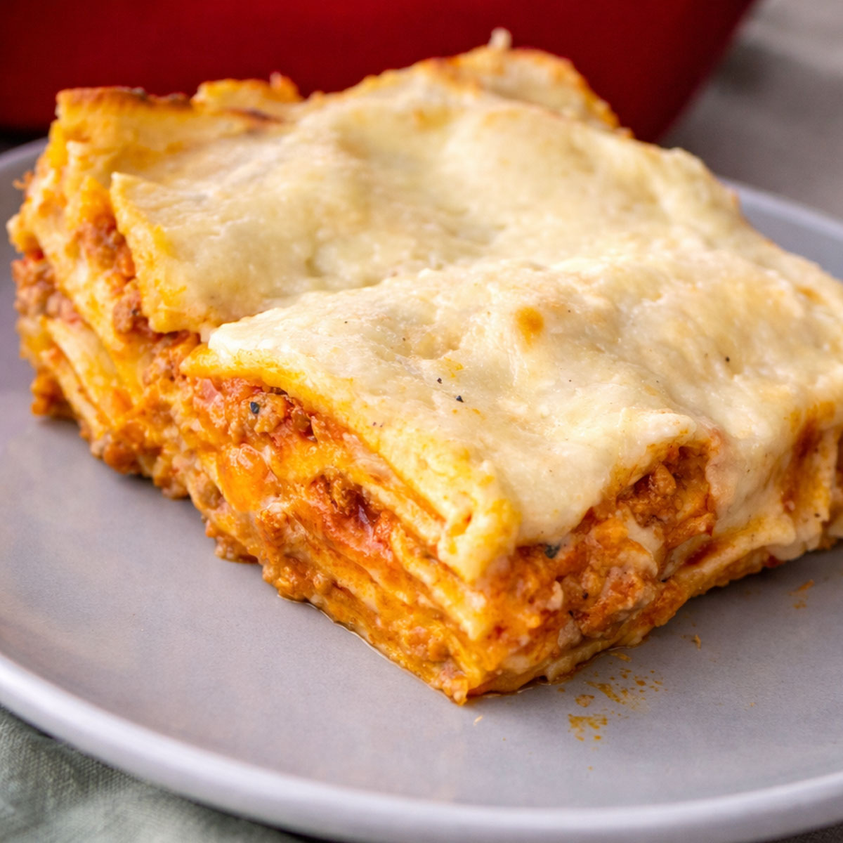 Slice of easy no-boil lasagna with pork Bolognese, béchamel sauce, and melted cheese on a plate