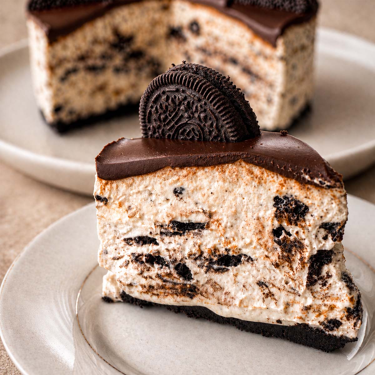 no-bake Oreo cheesecake slice with chocolate ganache on a plate, creamy cookies and cream filling and Oreo crust
