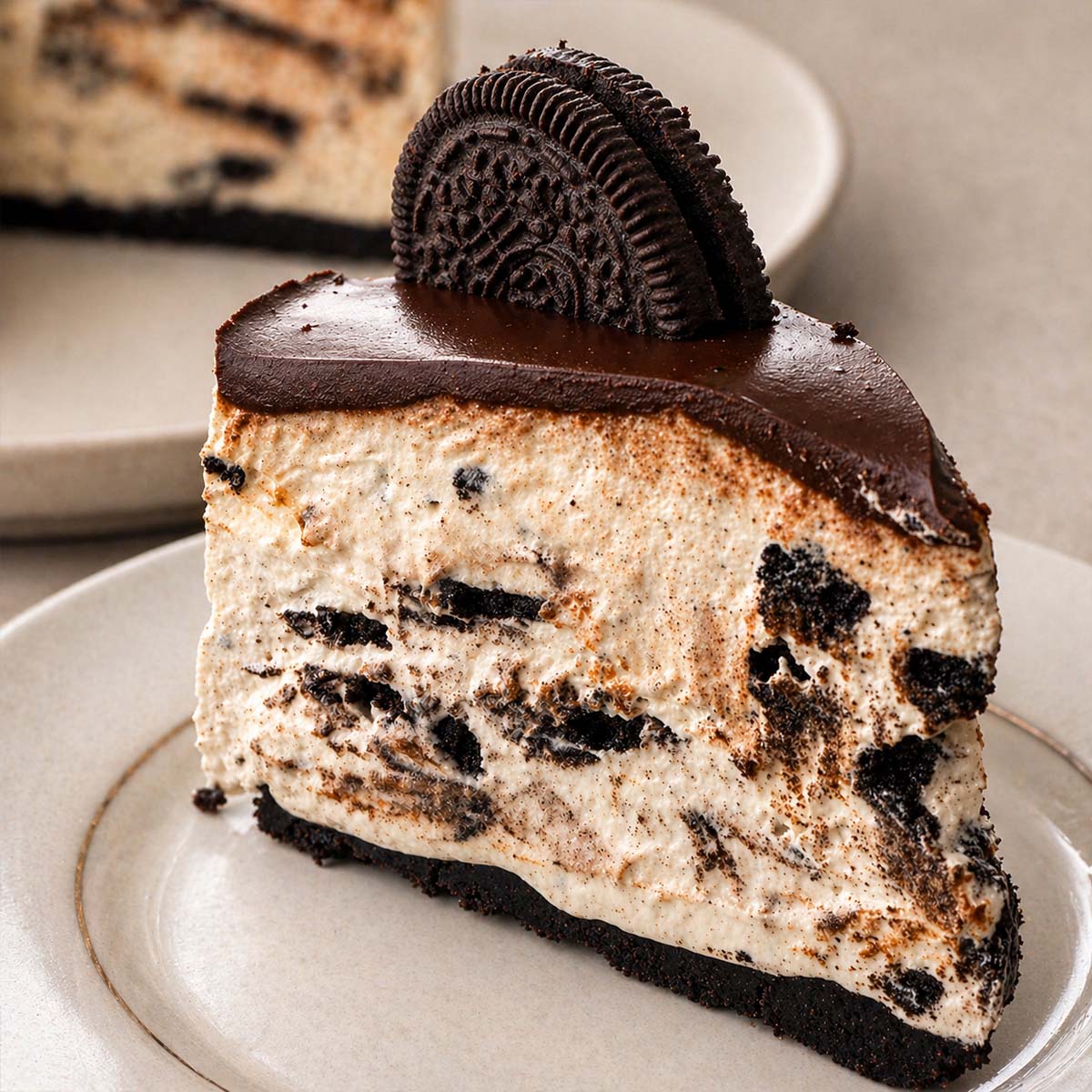 slice of no-bake Oreo cheesecake with chocolate topping on a plate, creamy cookies and cream filling and oreo cookie crust