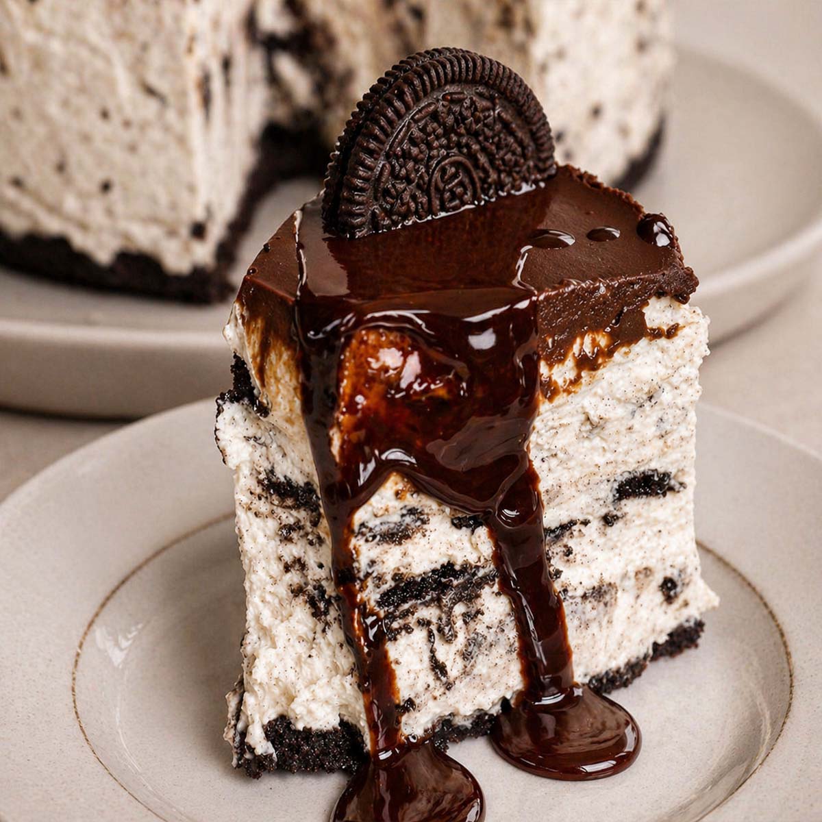 slice of no-bake Oreo cheesecake with chocolate ganache and syrup drizzle, creamy cookies and cream filling on a plate