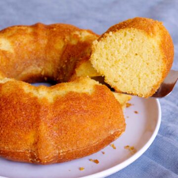 orange juice cake bundt with slice lifted on a cake server showing soft moist crumb on a white plate