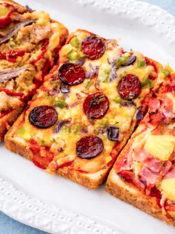 pizza toast with three toppings on sandwich bread, tuna and peppers, chorizo with vegetables, and ham with pineapple, baked with melted cheese on a white plate