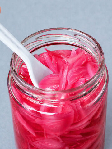 pickled red onions in glass jar with white spoon