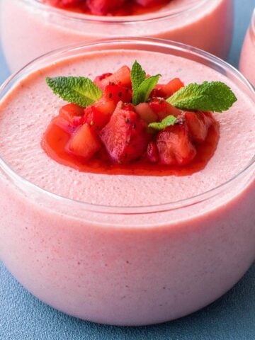 Strawberry mousse in a glass dessert cup topped with fresh strawberries and mint