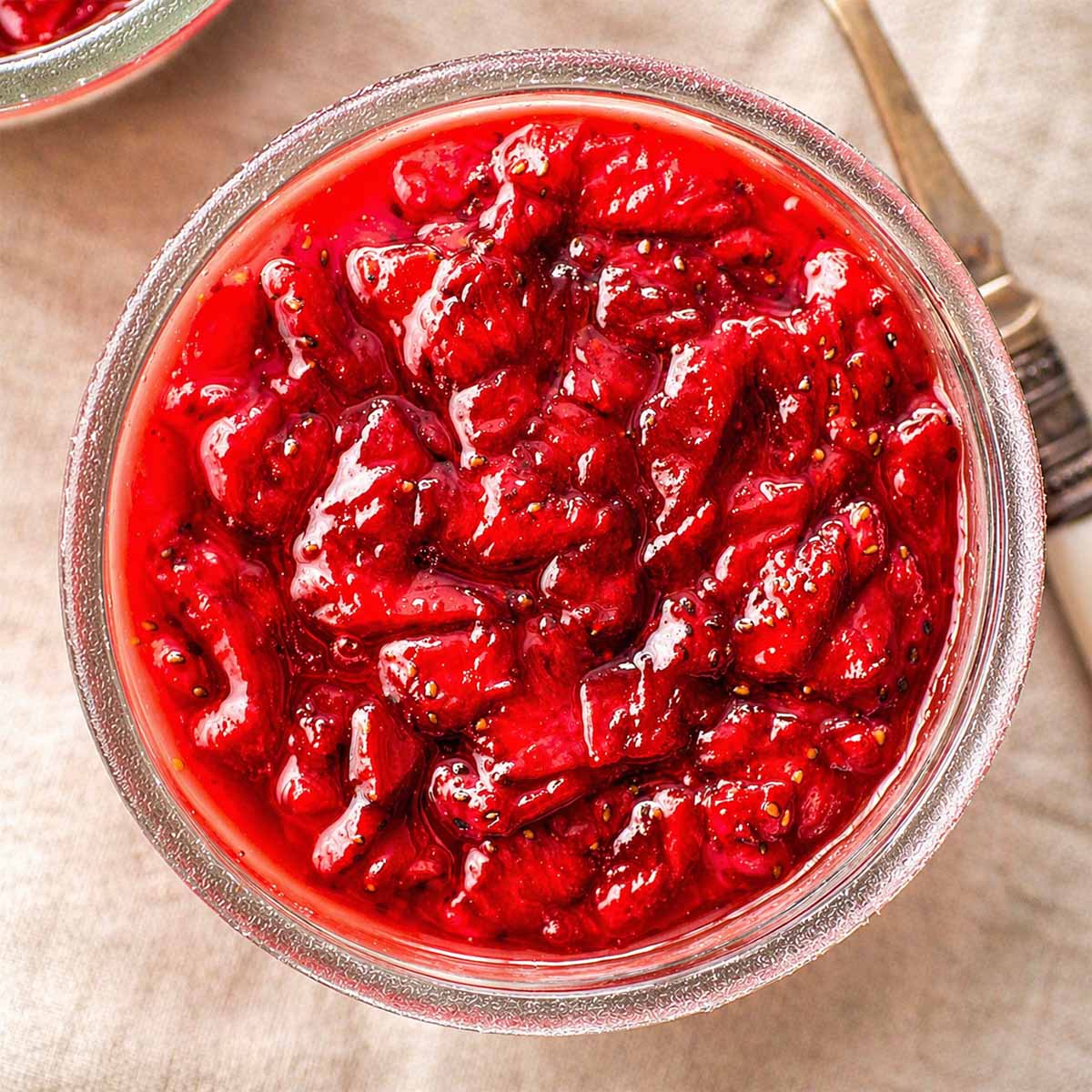 Close-up of strawberry pudding in a glass, topped with thick homemade strawberry jam.
