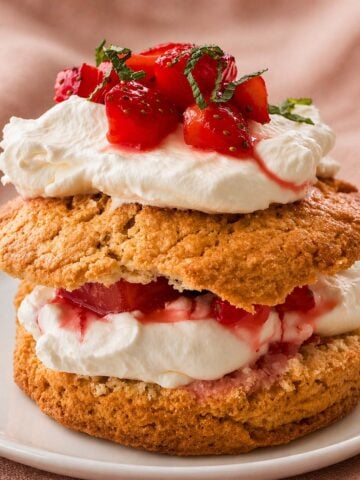 strawberry shortcake with whipped cream and fresh strawberries on a white plate