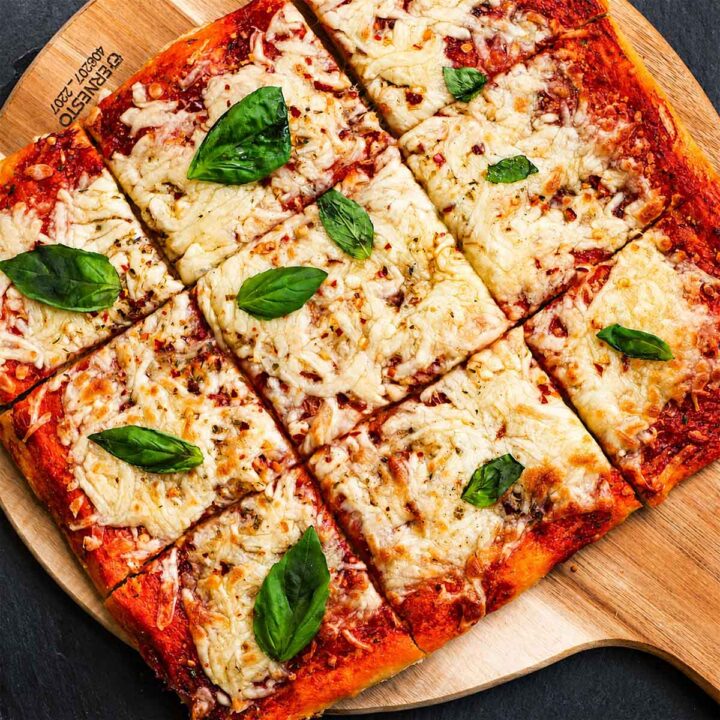 No Knead Pizza Dough baked into a crispy homemade sheet pan pizza with melted mozzarella cheese and fresh basil leaves