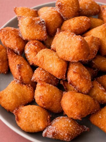 Apple fritters coated in sugar on a plate, golden and crisp with a soft center