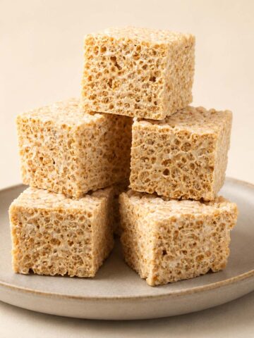 Brown Butter Rice Crispy Treats stacked on a ceramic plate with chewy marshmallow texture and golden brown butter flavor
