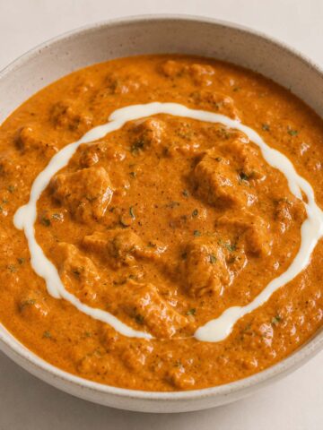 Creamy homemade butter chicken served in a bowl with tender chicken pieces and a rich spiced tomato curry sauce topped with cream swirl