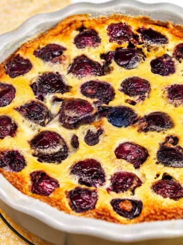 Cherry Clafoutis fresh from the oven in a ceramic baking dish with golden custard and juicy baked cherries