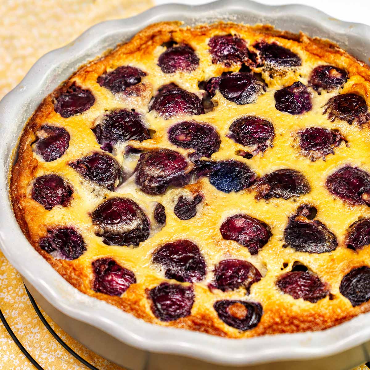 Cherry Clafoutis fresh from the oven in a ceramic baking dish with golden custard and juicy baked cherries