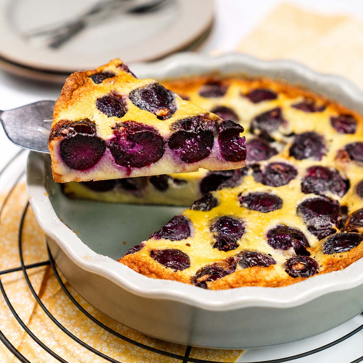 Cherry Clafoutis with a slice lifted from the baking dish showing creamy custard and juicy baked cherries