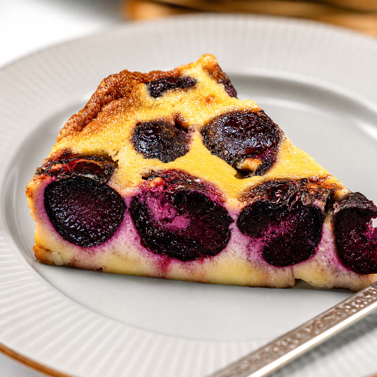 Slice of Cherry Clafoutis on a plate with creamy baked custard and sweet roasted cherries