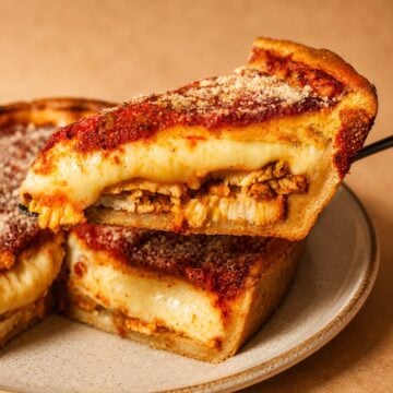 Close up Chicago Style Deep Dish Pizza with thick golden crust, melted cheese, and a slice lifted on a spatula