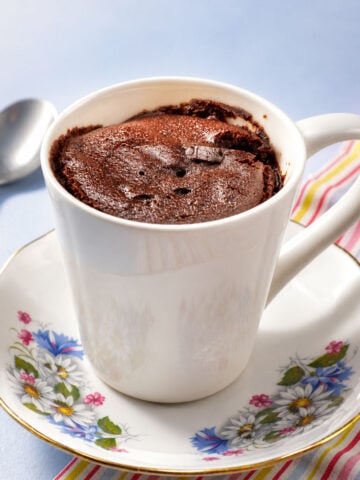 Chocolate mug cake in a white ceramic mug served on a floral saucer with a soft chocolate center