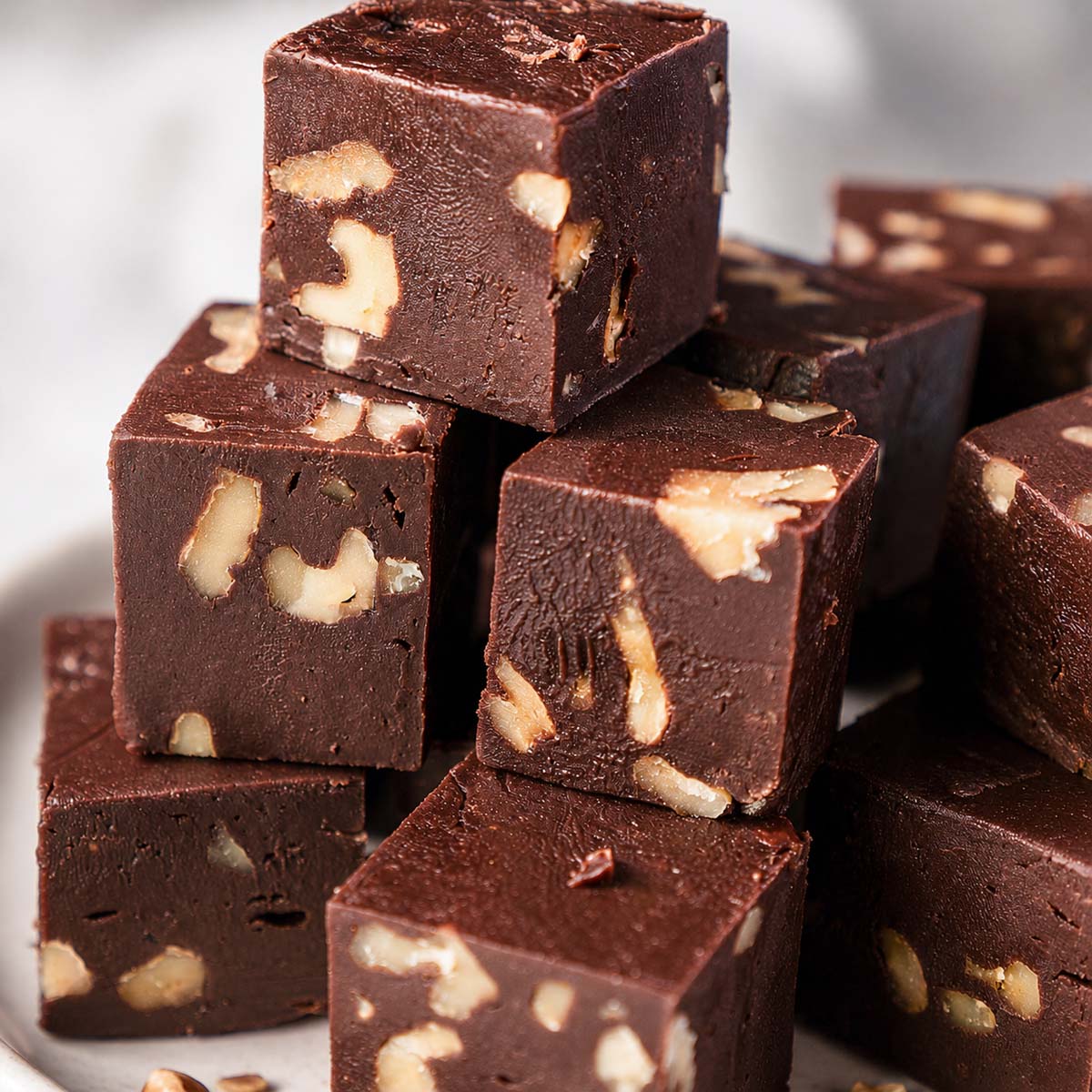Close-up of chocolate walnut fudge stacked into rich creamy squares filled with crunchy walnut pieces