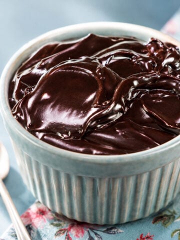 Chocolate frosting with cocoa powder in a blue ramekin
