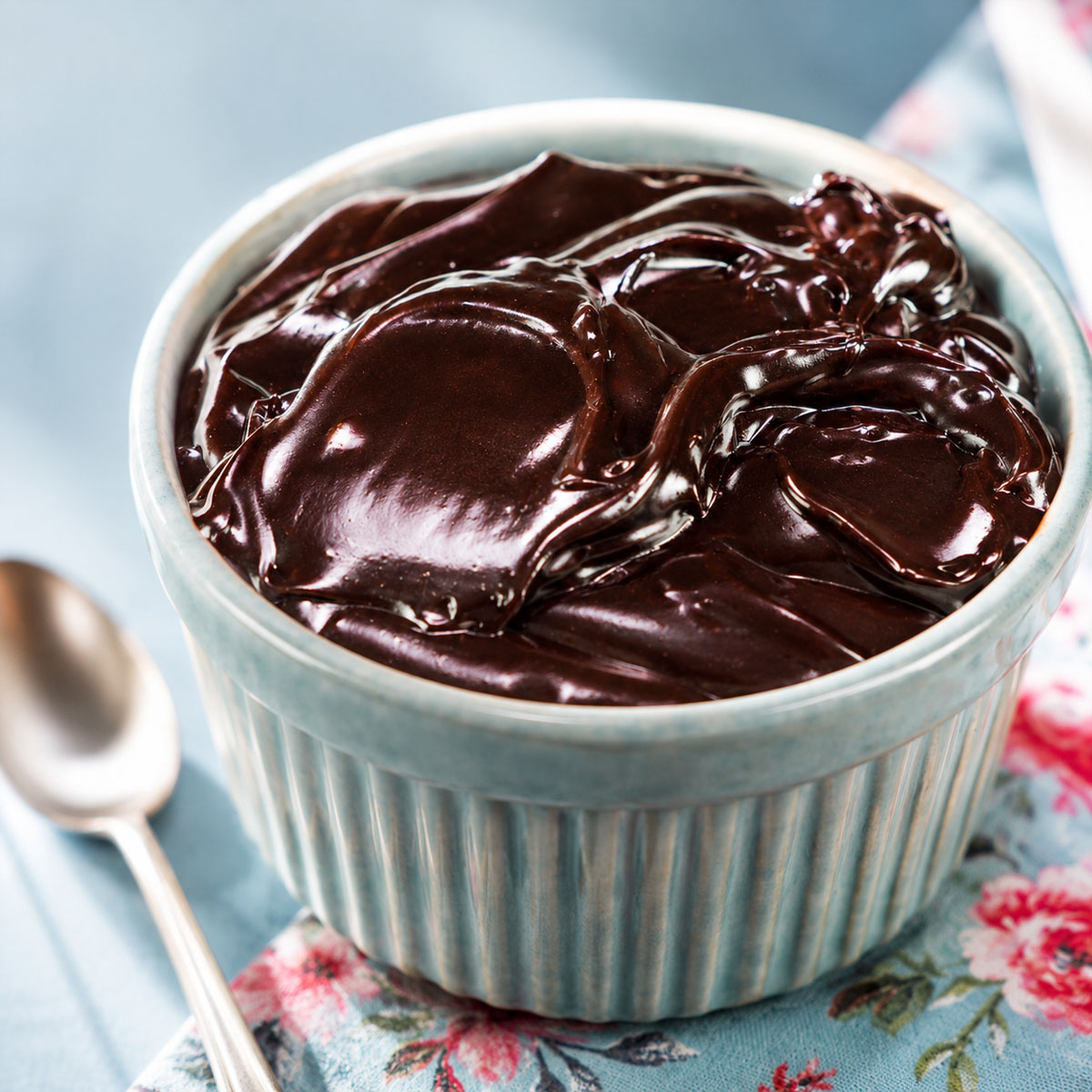 Chocolate frosting with cocoa powder in a blue ramekin