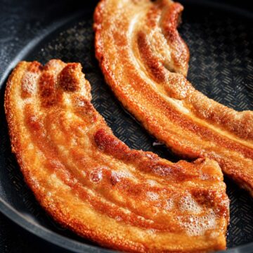 Crispy Pork Belly Chicharrones frying in a pan with golden, bubbly crackling and rich caramelized edges