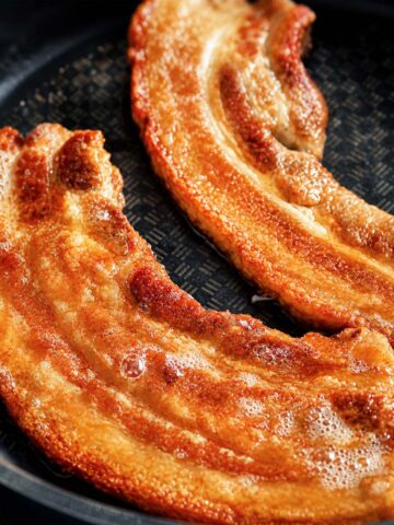 Crispy Pork Belly Chicharrones frying in a pan with golden, bubbly crackling and rich caramelized edges