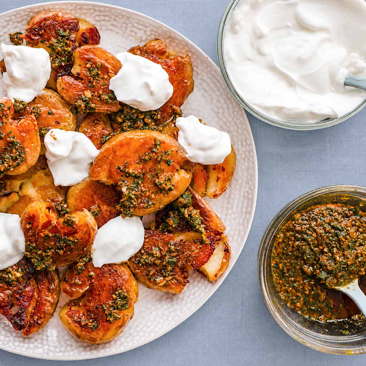 Easy crispy smashed potatoes with garlic-chili sauce and mayonnaise, served on a plate with side bowls