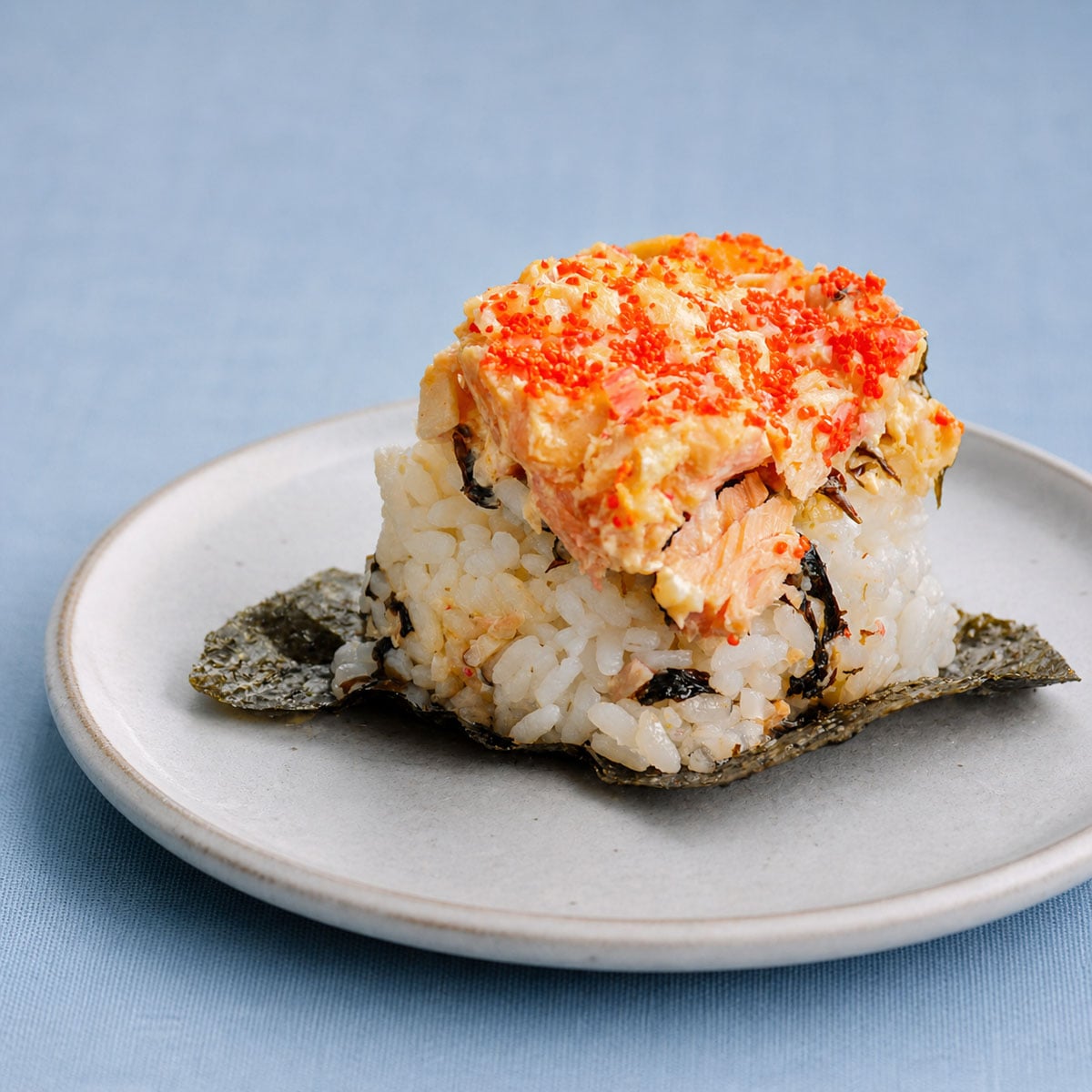 easy salmon sushi bake piece on plate with rice, nori base, creamy seafood topping