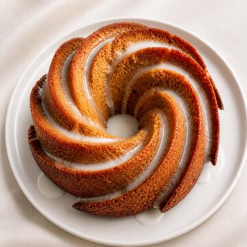 Easy lemon Bundt cake with glaze on a white plate, soft moist texture and golden crust