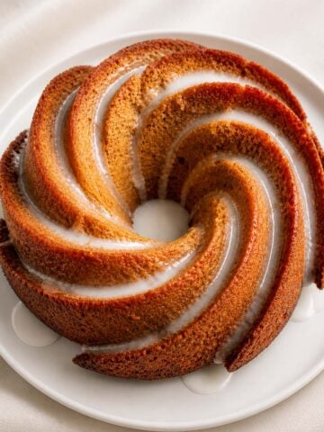 Easy lemon Bundt cake with glaze on a white plate, soft moist texture and golden crust