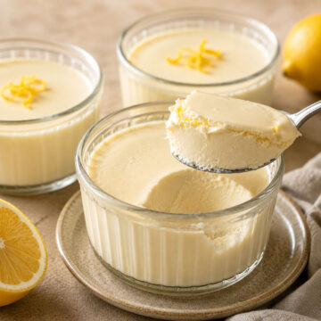 Creamy lemon posset in glass ramekins with a spoonful lifted above