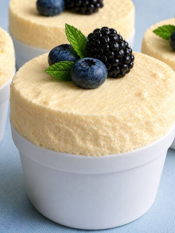 Chilled lemon soufflé in white ramekins topped with fresh blueberries and blackberries