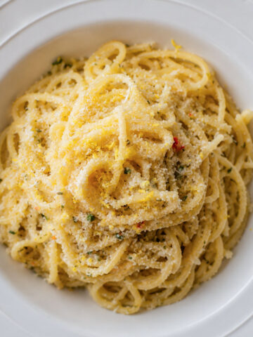 Creamy lemon garlic spaghetti topped with Parmesan cheese in a white bowl, featuring a silky garlic butter sauce and fresh lemon flavor.