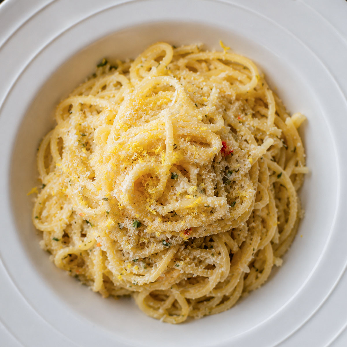 Creamy lemon garlic spaghetti topped with Parmesan cheese in a white bowl, featuring a silky garlic butter sauce and fresh lemon flavor.