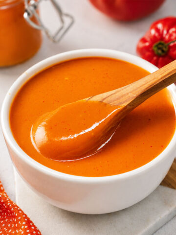 Creamy mango habanero sauce in a white bowl with a wooden spoon,