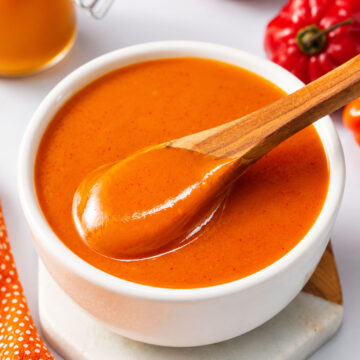 closeup Creamy mango habanero sauce in a white bowl with a wooden spoon,