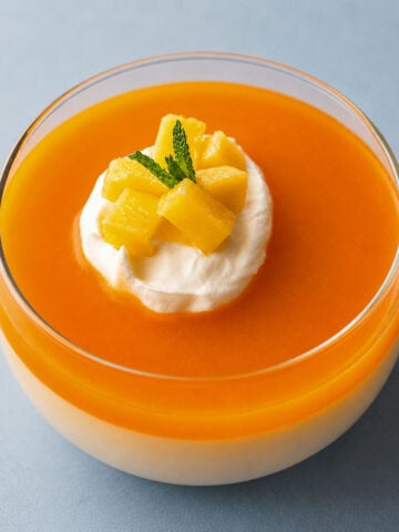 Creamy mango pudding cup topped with whipped cream, fresh mango pieces, and mint