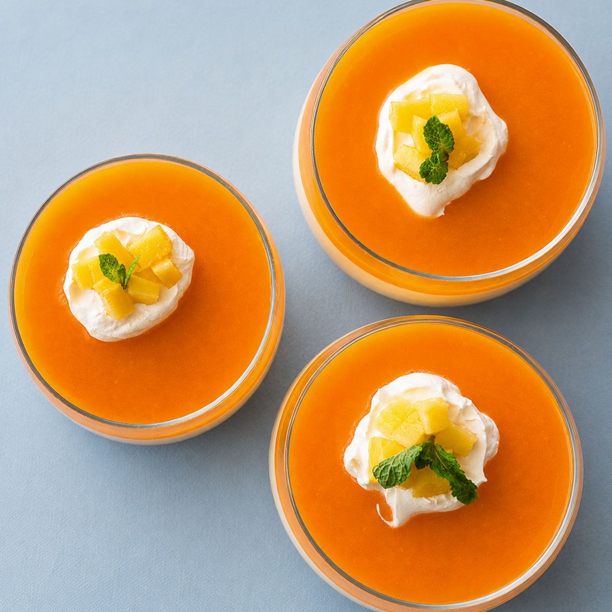 Top view of creamy no-bake mango pudding with condensed milk topped with whipped cream, diced mango, and fresh mint