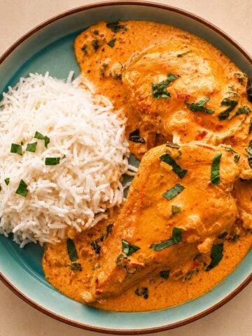 Creamy Marry Me Chicken served with fluffy white rice in a blue ceramic bowl with rich parmesan sun-dried tomato sauce and fresh basil garnish