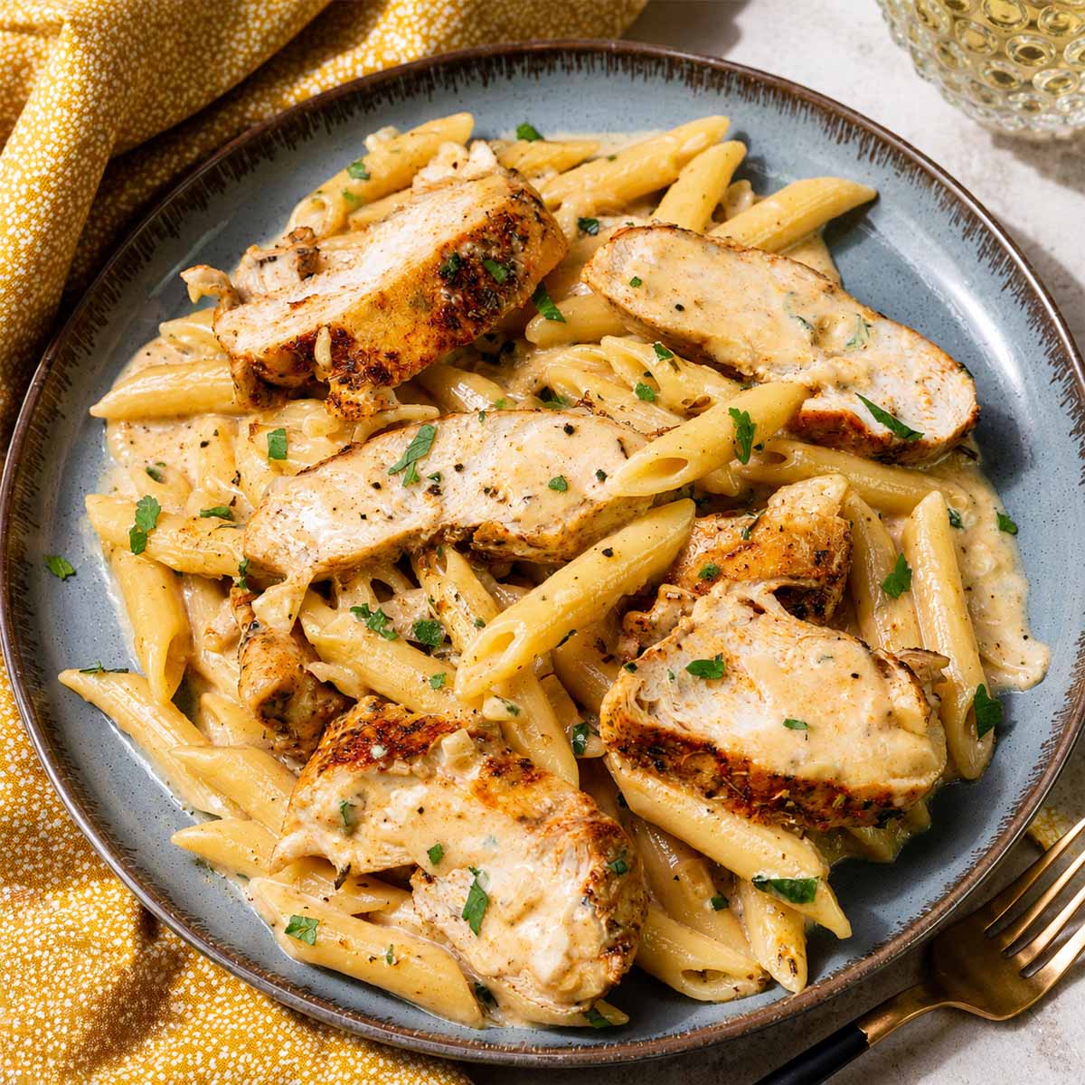 One-Pan Creamy Garlic Parmesan Chicken Pasta Recipe served in a ceramic bowl with golden seared chicken, creamy parmesan sauce, and tender penne pasta.
