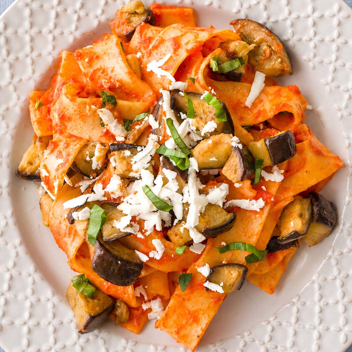 Close up Pasta Alla Norma (Sicilian Eggplant Pasta) served with tomato sauce, fried eggplant, fresh basil, and grated ricotta salata