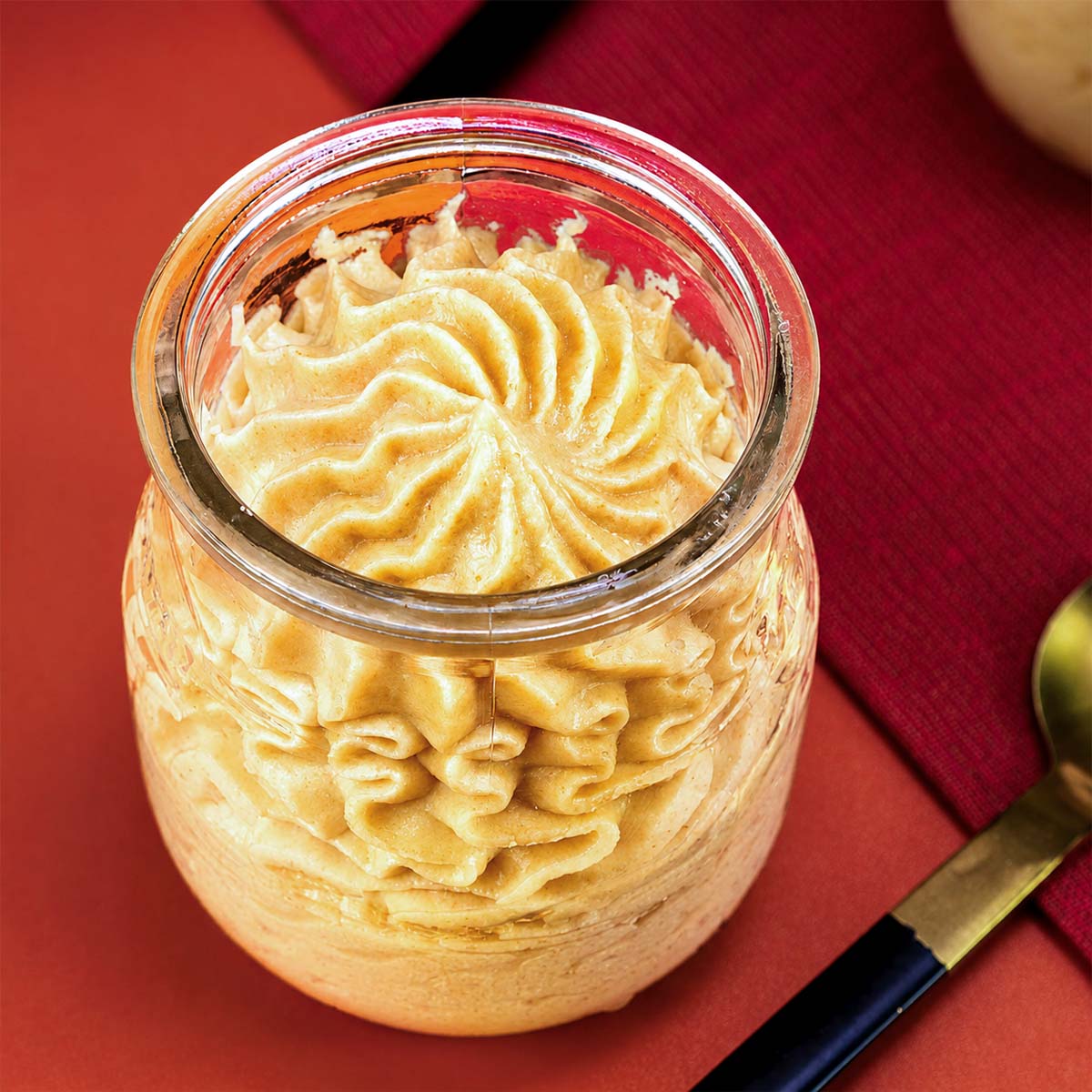 Peanut Butter Mousse piped into a glass jar with a creamy swirled top and spoon