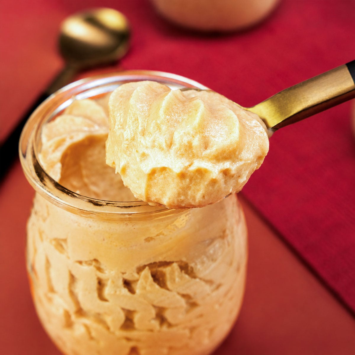 Spoonful of creamy Peanut Butter Mousse held above a glass jar, showing its light and fluffy texture