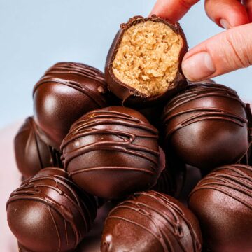 Close-up of a bitten peanut butter ball with a creamy peanut butter center and dark chocolate coating.