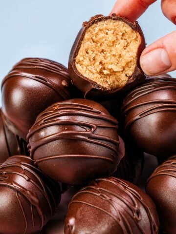 Close-up of a bitten peanut butter ball with a creamy peanut butter center and dark chocolate coating.
