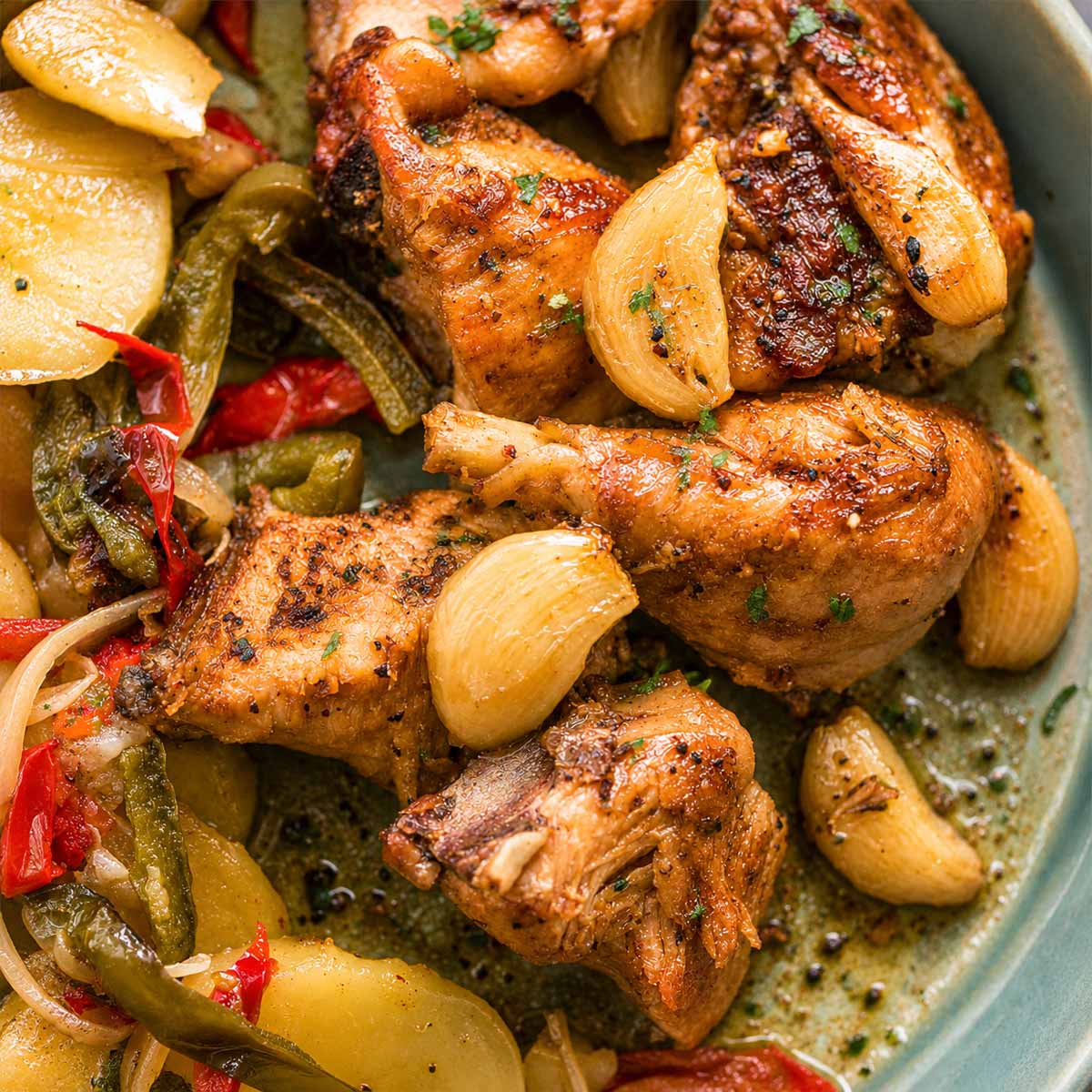 close up Spanish Garlic Chicken (Pollo al Ajillo) served with peppers, and potatoes