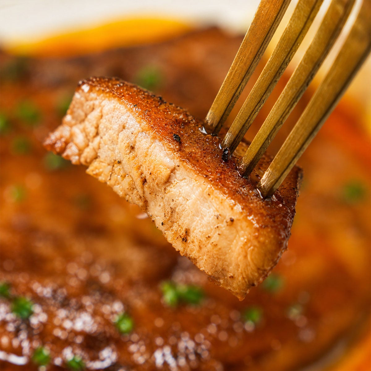 Close-up of Juicy Baked Pork Loin Chops showing the tender inside and crispy golden crust on a fork
