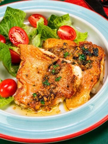 Pan Seared Rock Fish with garlic herb butter sauce served with fresh lettuce and cherry tomatoes